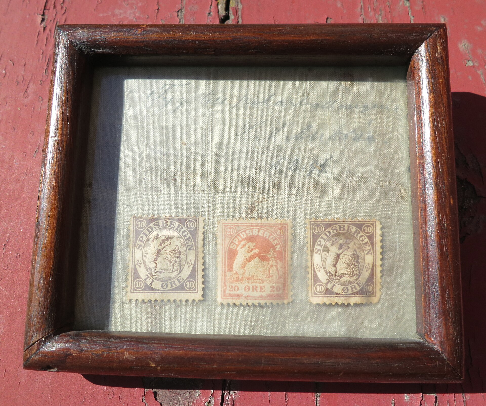 Gerahmtes Stück Stoff mit Aufschrift „Tyg till polarballongen S. A. Andrée 5.8.96“ und drei Spitzbergen-Briefmarken