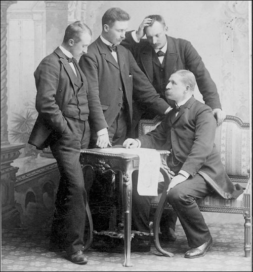 Atelierporträt von vier Männern um einen Tisch mit Karte: Vilhelm Swedenborg, Nils Strindberg, Knut Frænkel und S. A. Andrée (sitzend)