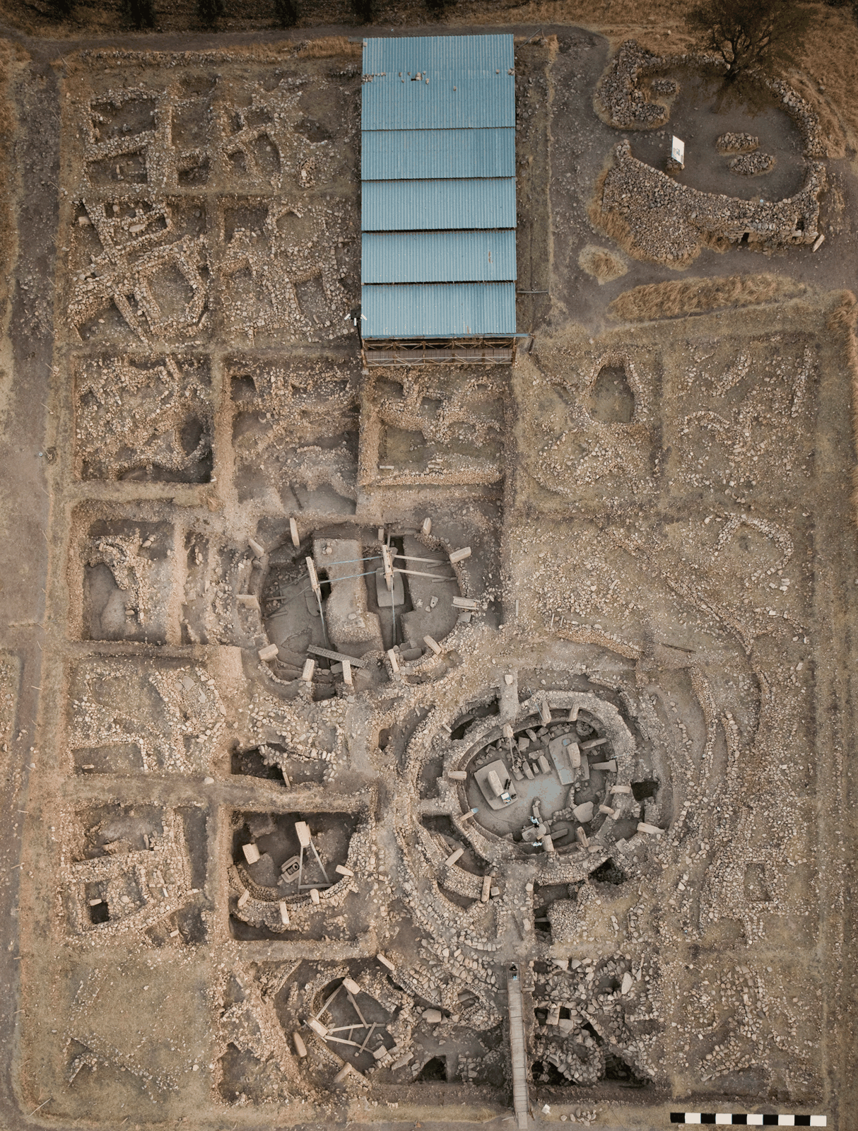 Senkrechtes Luftbild des Hauptgrabungsbereichs von Göbekli Tepe mit den runden Kammbauten A, B, C und D unter dem modernen Schutzdach.