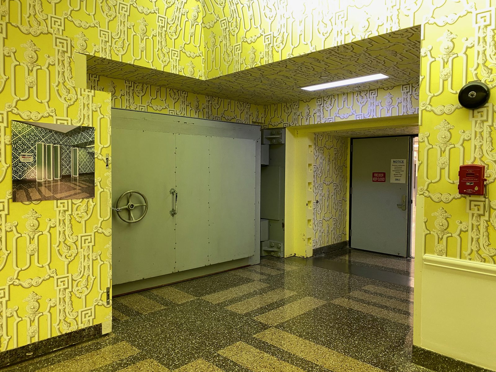 Massives graues Stahldrucktor der Mosler Safe Co. mit Handrad am Bunkereingang in der mit gelber Dorothy-Draper-Tapete verkleideten Colonial Hall des Greenbrier Resorts.