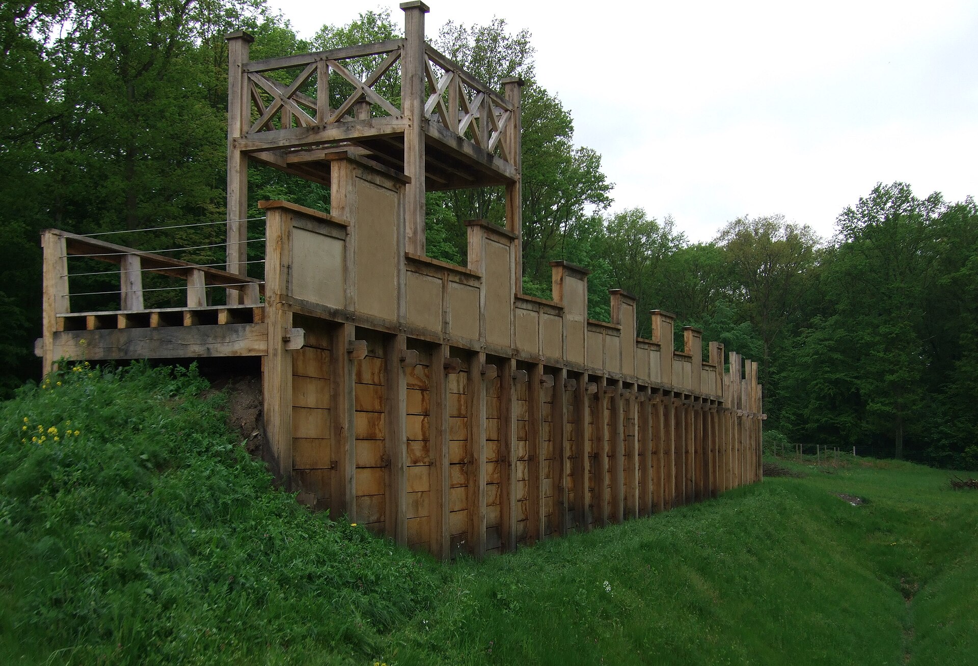 Nachbau der Holz-Erde-Mauer mit Turm und Rampe, seitlich der grasbewachsene Graben