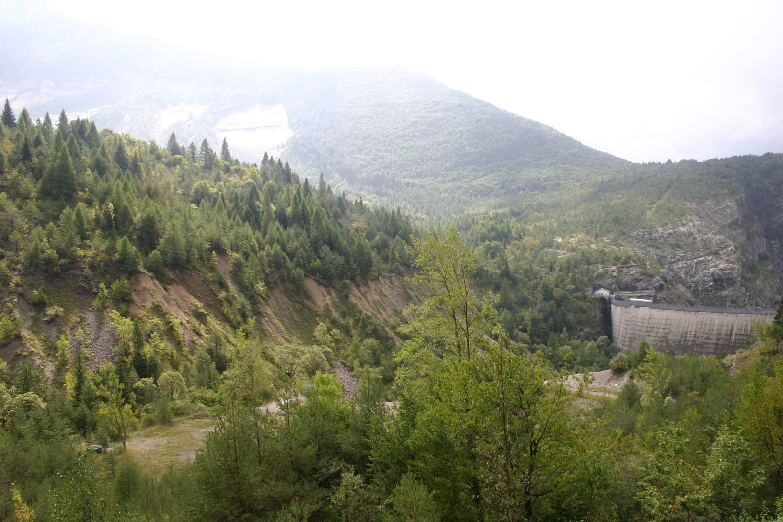 Blick von der Krone der Vajont-Staumauer auf den haushoch hinter der Betonmauer aufgetürmten Fels- und Schuttkörper des abgerutschten Monte Toc, der das ehemalige Staubecken vollständig verfüllt.